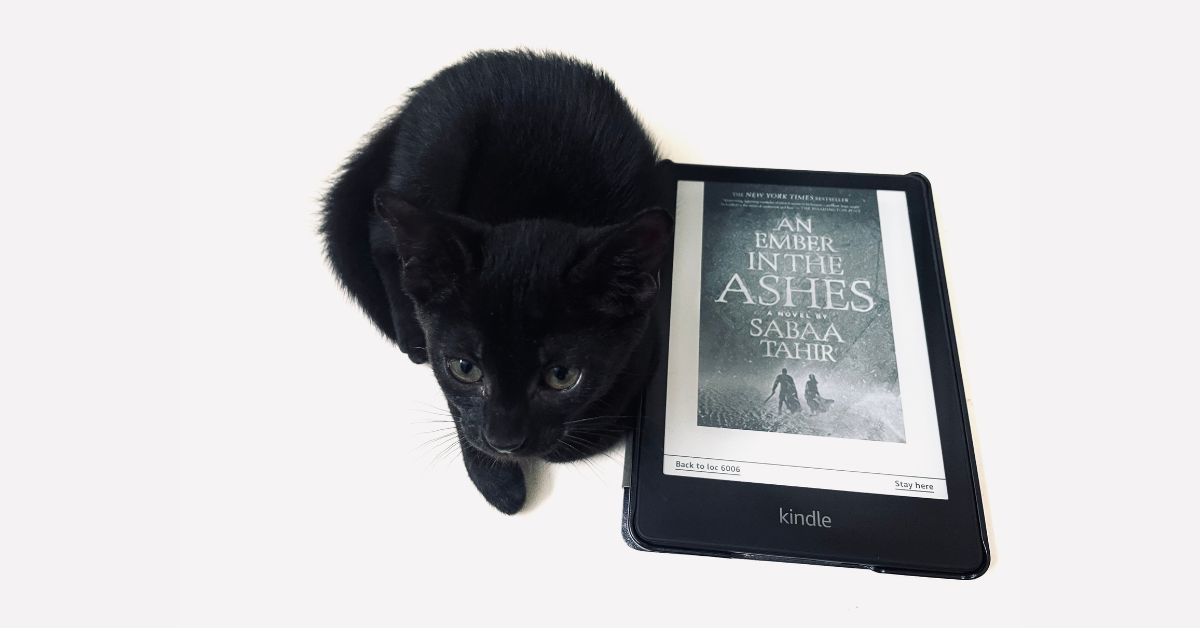 An Ember in the Ashes book on Kindle with a black cat
